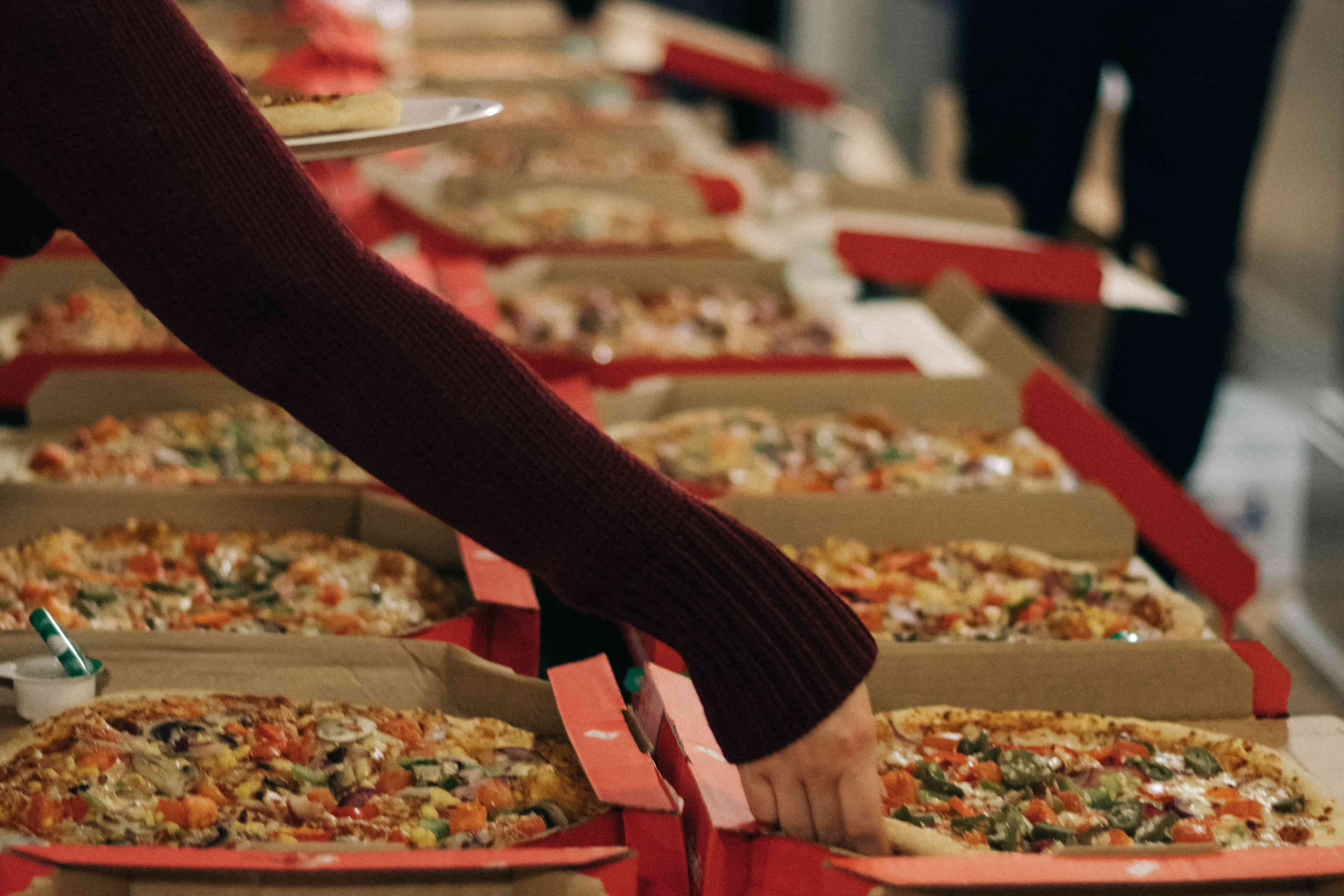 A woman picking up a slice of Dominos pizza