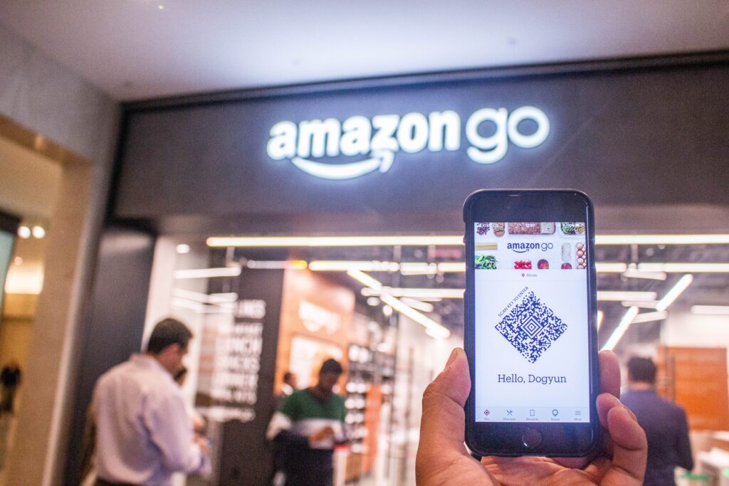 Mano che tiene un telefono fuori dal negozio Amazon Go