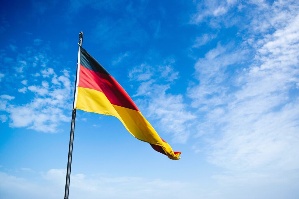 German flag blowing against a blue sky