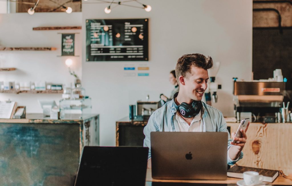 Man using smartphone and Mac Book and smiling