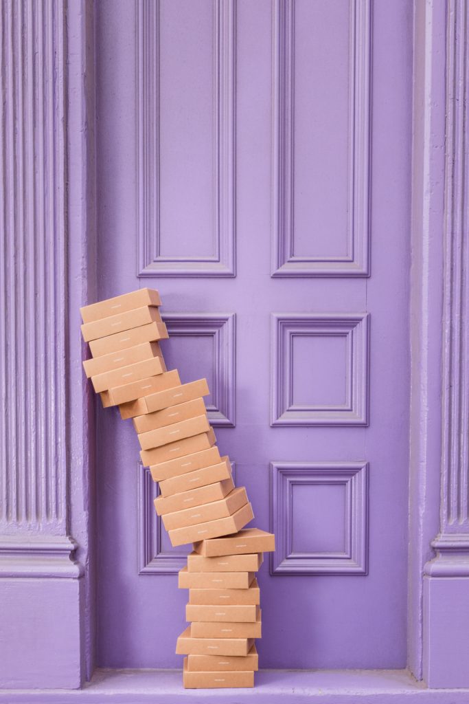 Pile de boîtes en carton adossées contre un mur violet