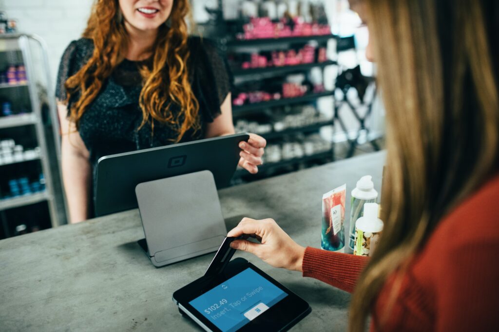 Customer paying by card as she buys products from a shop assistant