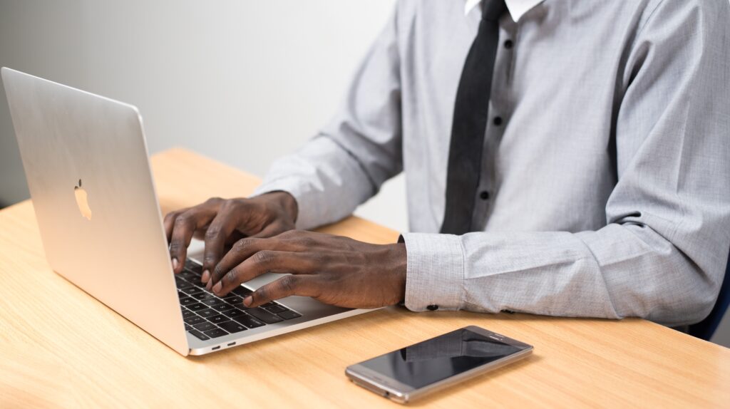 Man sitting at laptop with a mobile phone beside him