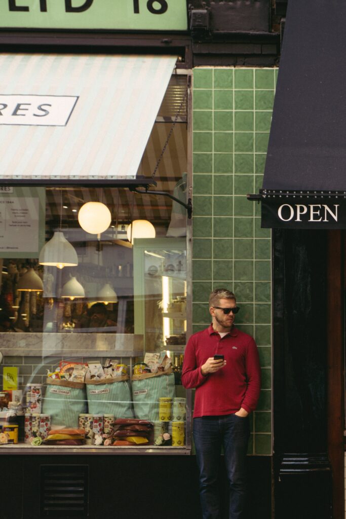 Homme utilisant un smartphone en attendant devant un magasin