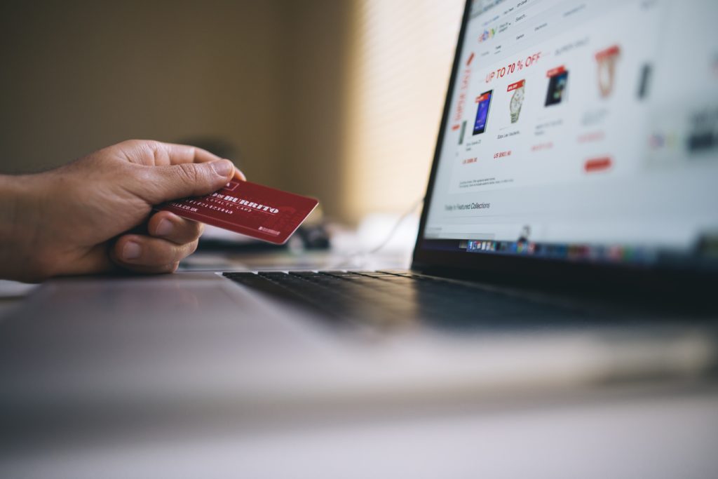 Person looking at a laptop and holding a credit card